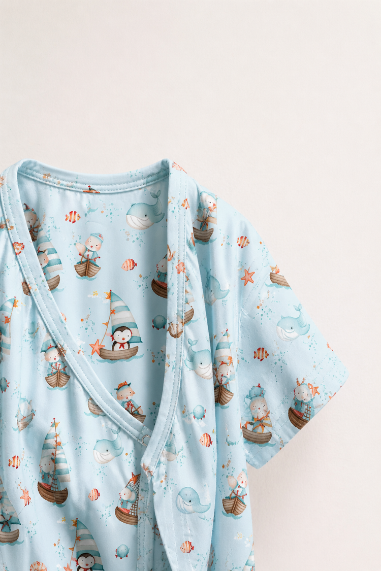 Baby wearing Anaario Ocean Sailor Wrap sky blue with boats whales penguins ocean prints romper, newborn to 24 months
