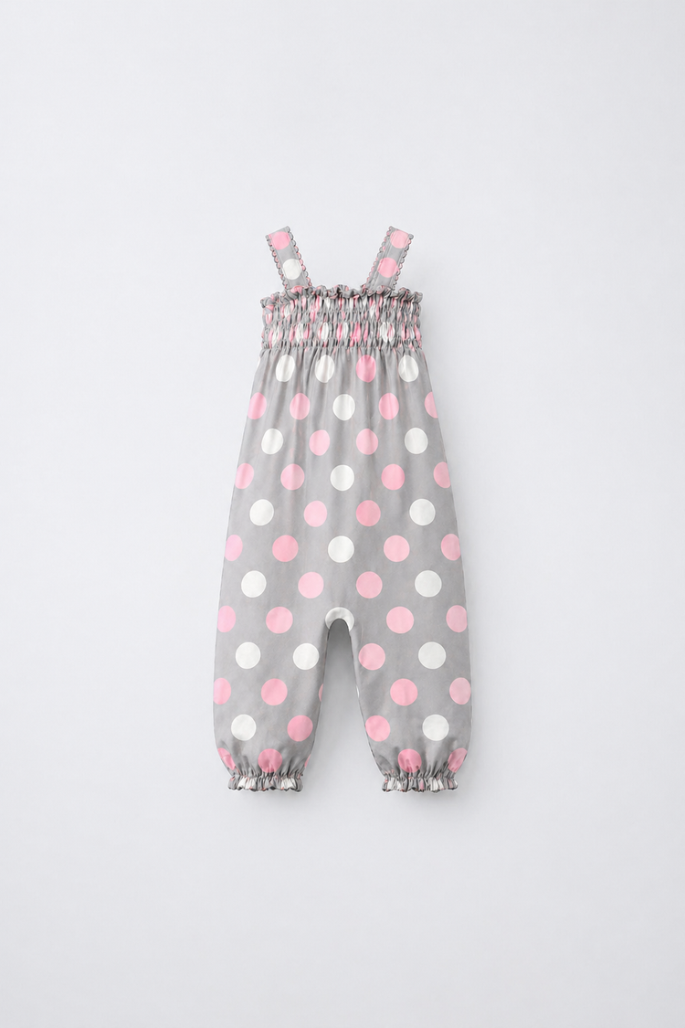 Baby wearing Anaario Blush Dot Smocked grey romper with pink and white polka dots, newborn to 24 months