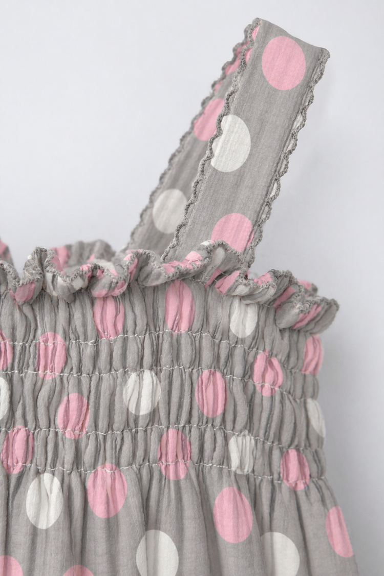 Baby wearing Anaario Blush Dot Smocked grey romper with pink and white polka dots, newborn to 24 months