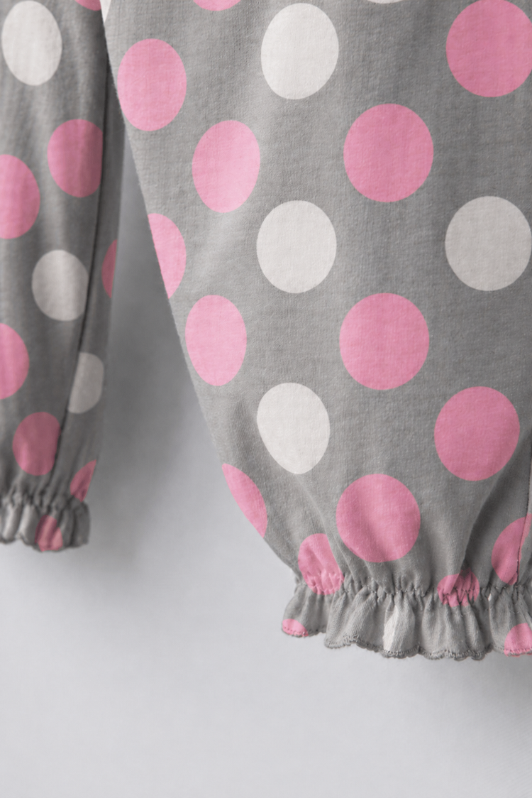 Baby wearing Anaario Blush Dot Smocked grey romper with pink and white polka dots, newborn to 24 months