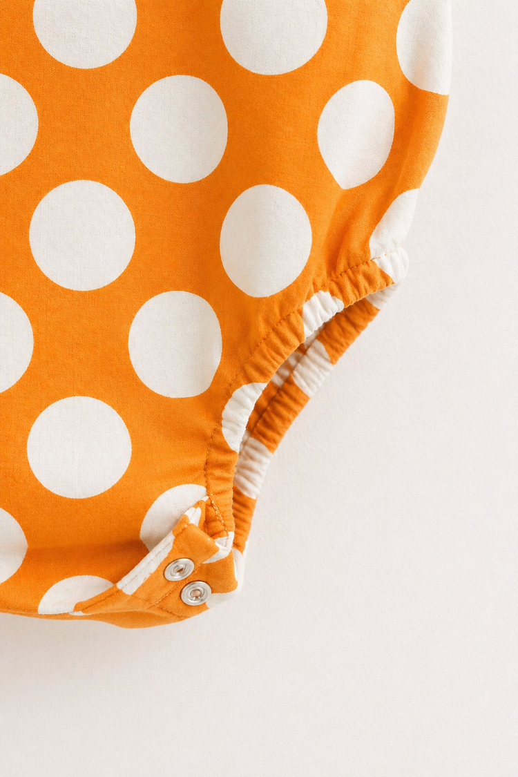 Baby wearing Anaario Orange White Polka Dot Sleeveless wrap-style romper, newborn to 24 months