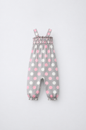 Baby wearing Anaario Blush Dot Smocked grey romper with pink and white polka dots, newborn to 24 months