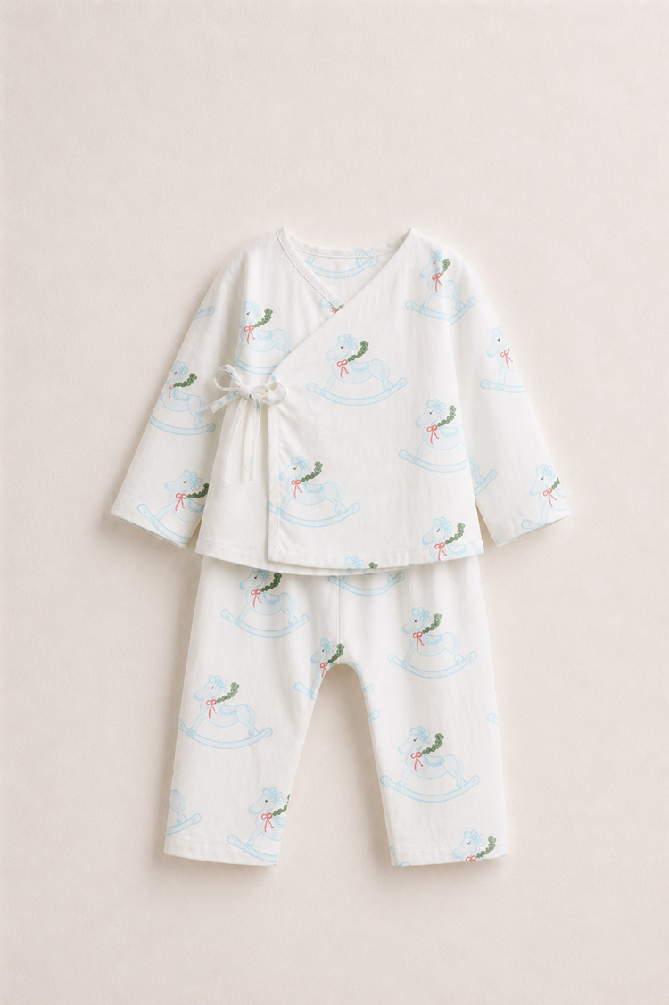 Baby wearing Anaario Rocking Horse Wrap ivory with soft blue rocking horse prints co-ord set, newborn to 24 months