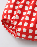 Baby wearing Anaario Cherry Check Bubble red and white gingham puff sleeve romper, newborn to 24 months
