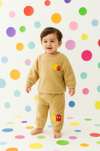 Baby wearing beige fleece set with Pac-Man patch