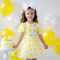 Girl wearing Anaario yellow organza party dress with hearts motif