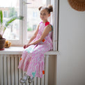 Girl wearing Anaario Sail Away maxi dress in white with pink dashed line print and colorful star appliques