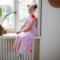 Girl wearing Anaario Sail Away maxi dress in white with pink dashed line print and colorful star appliques