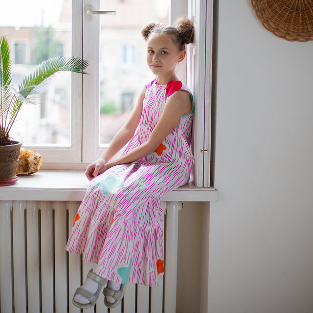 Girl wearing Anaario Sail Away maxi dress in white with pink dashed line print and colorful star appliques