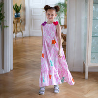 Girl wearing Anaario Sail Away maxi dress in white with pink dashed line print and colorful star appliques